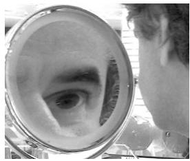 Fotografía de un ojo reflejado en un espejo de aumento.