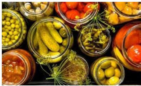 Varios botes de cristal con vegetales encurtidos (pepinillos, tomates, aceitunas).